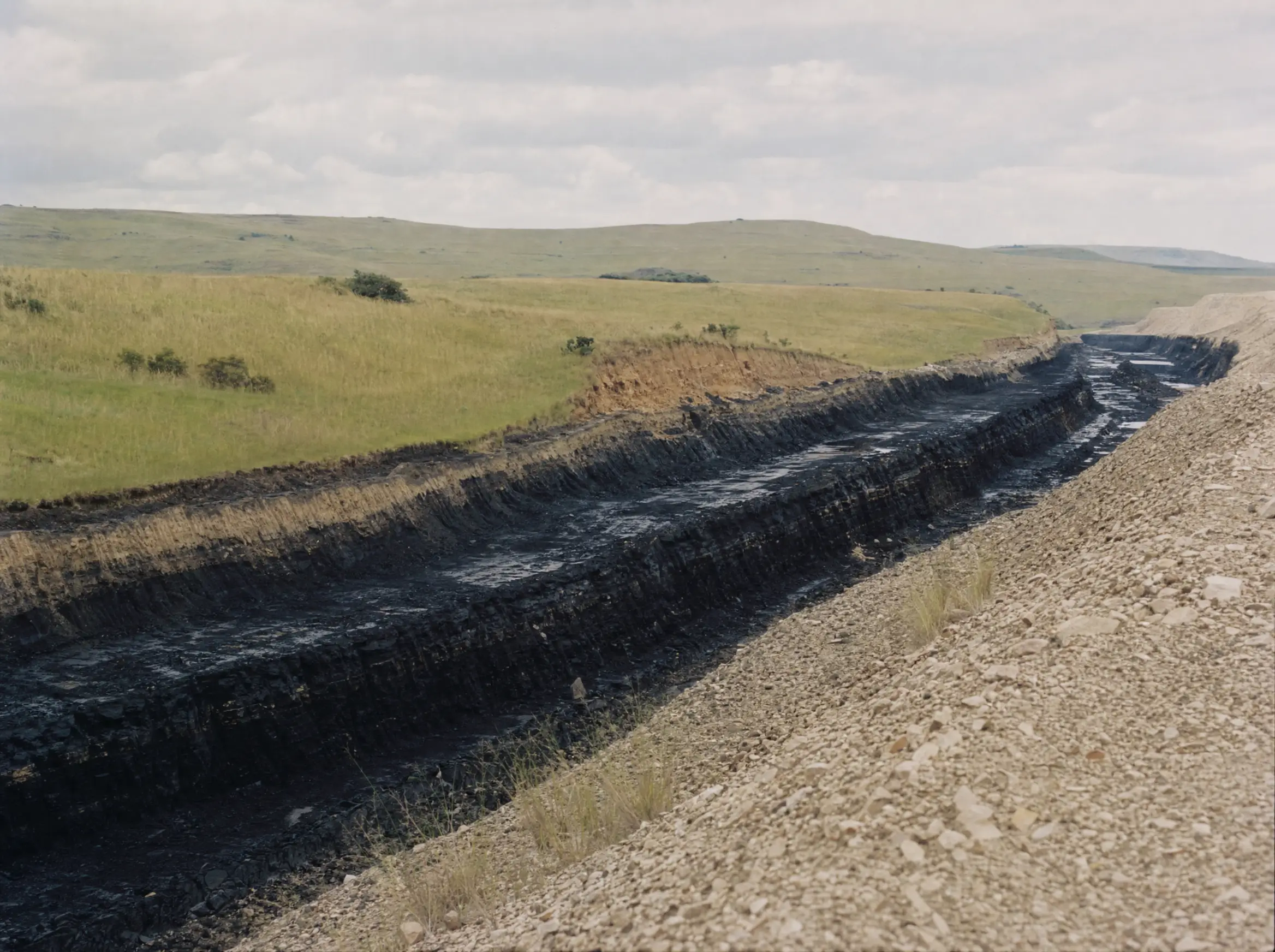The Natal Anthracite Mine strip cut running through green grassland at Vryheid, KwaZulu-Natal